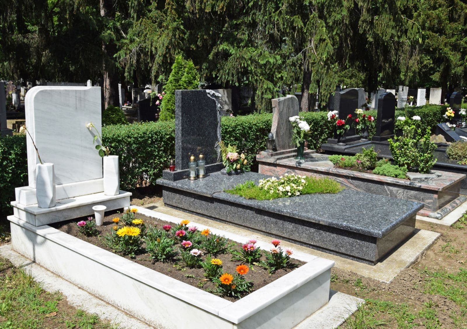 Monuments funeraires en granit blanc et noir fleuris dans un cimetiere